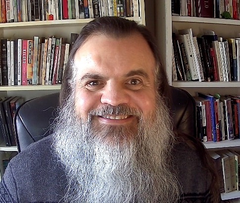 Bryan smiling in front of office books 2022 Feb -a